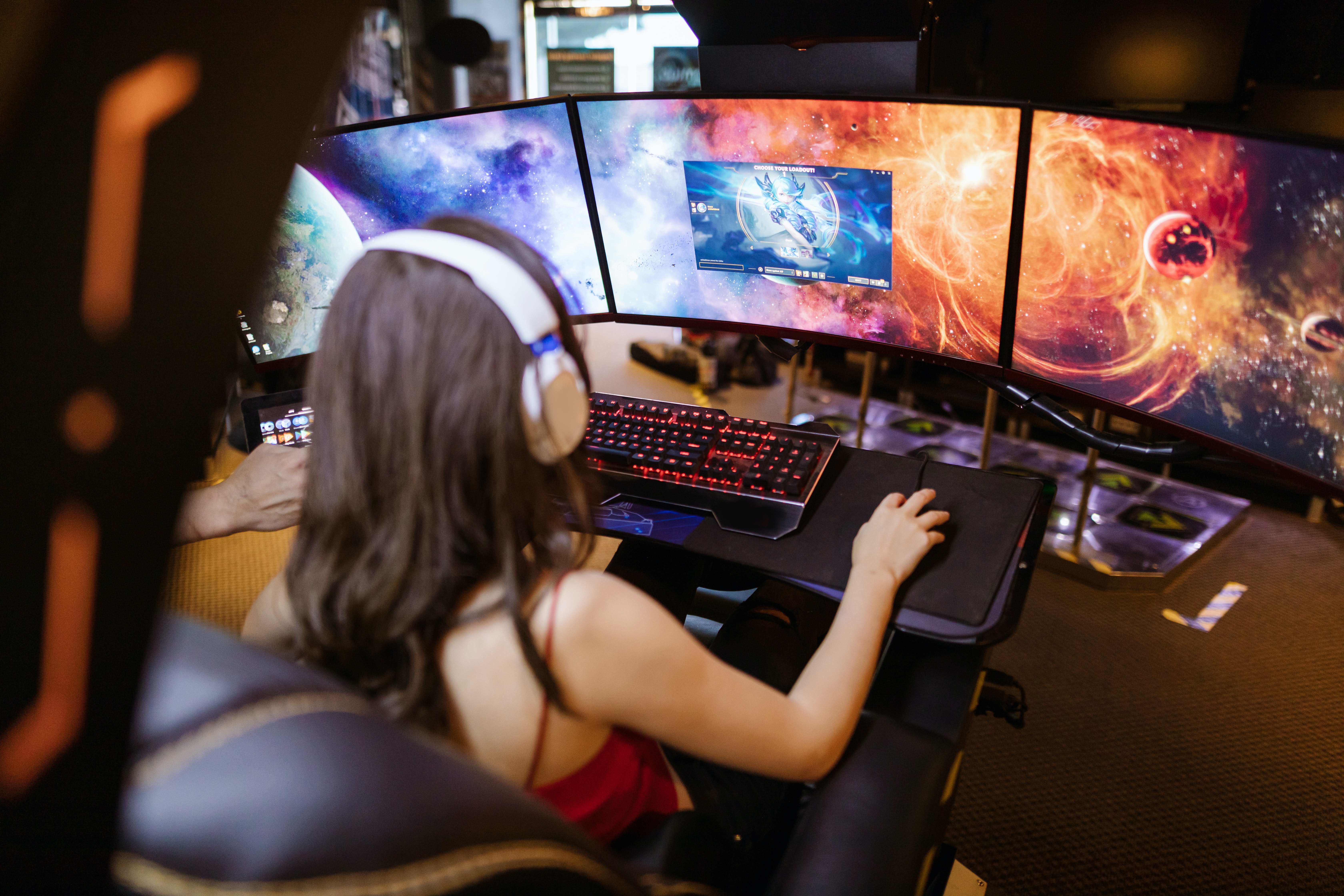 chica gamer jugando de espaldas con tres pantallas