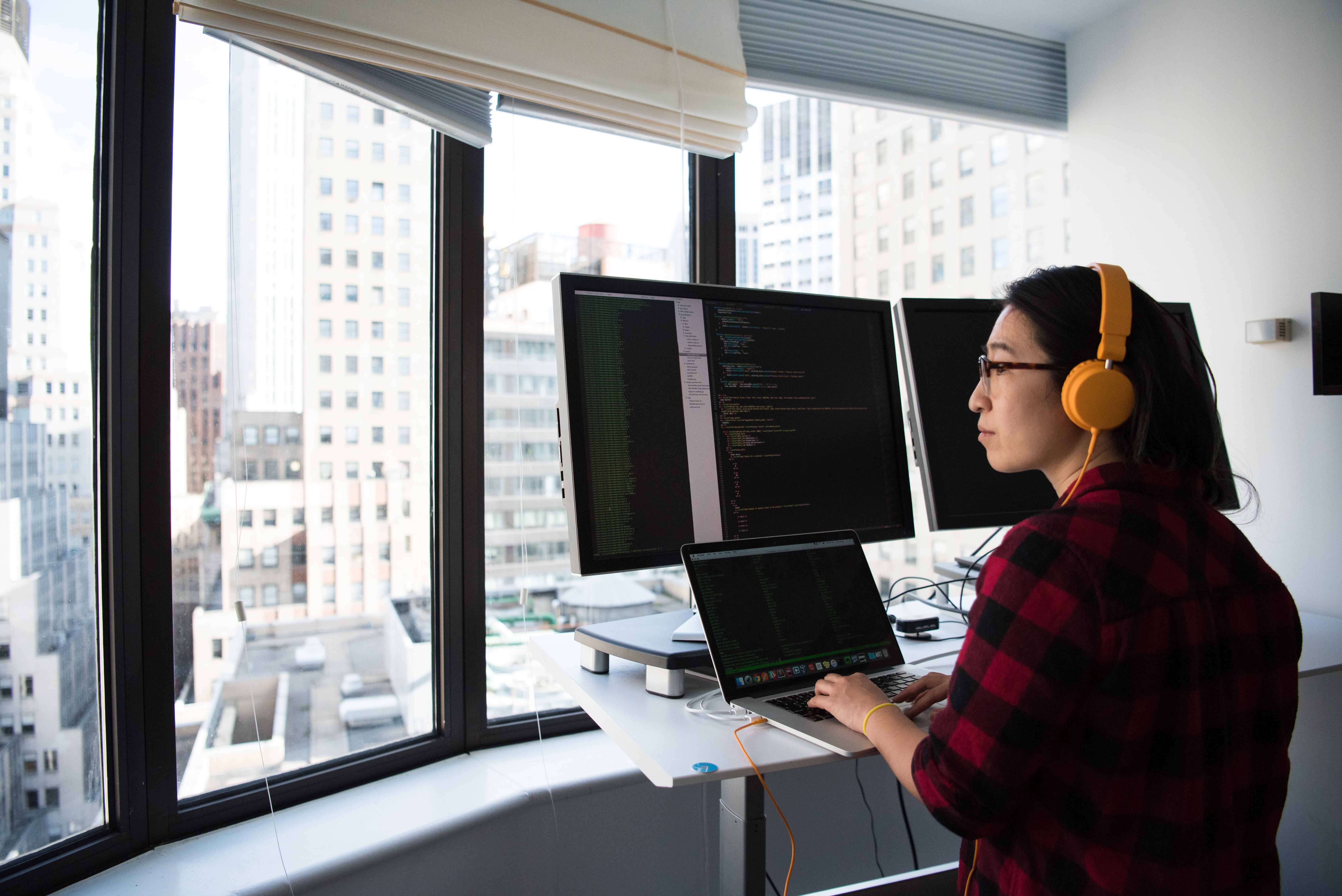 mujer programando con ventanas y vistas de edificios altos