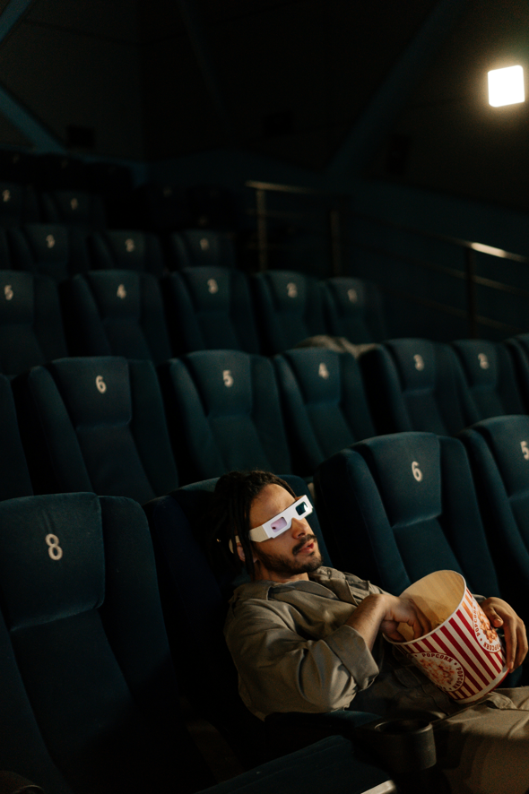 Butacas de cine con hombre sentado comiendo palomitas