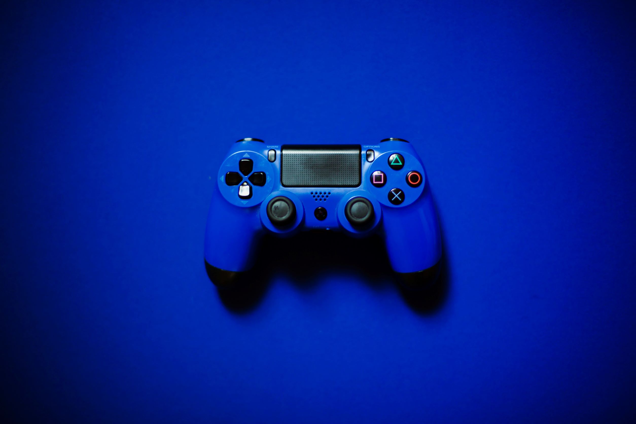 Mando de videoconsola de color azul sobre una mesa también azul