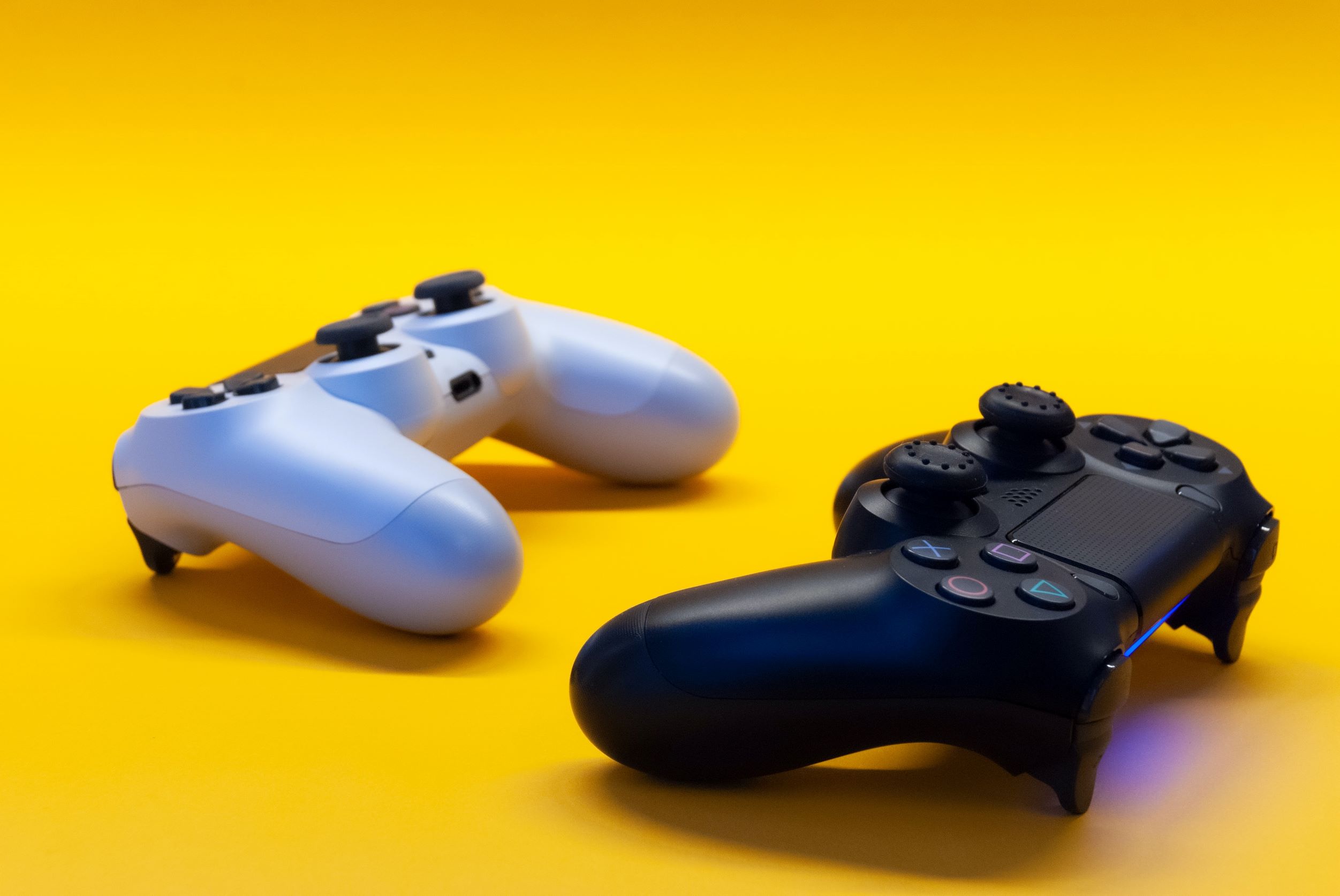 Dos mandos de videoconsola de colores blanco y negro posados en una mesa amarilla
